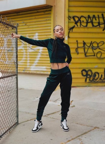 a woman leaning against a fence with her arms outstretched