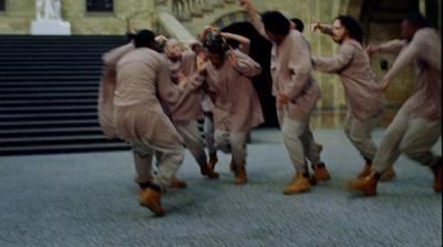 a group of men in tan suits are dancing