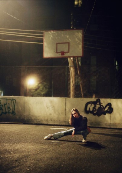 a woman sitting on the ground in front of a basketball hoop