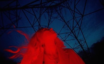 a woman with red hair standing in front of a red light