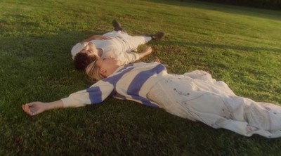 a young boy laying on the ground in a field