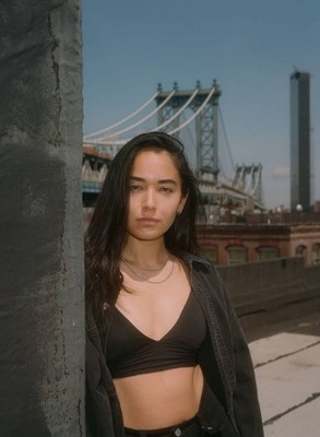 a woman standing next to a pole in front of a bridge