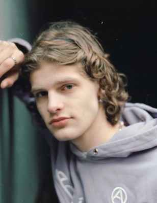 a young man with curly hair wearing a hoodie