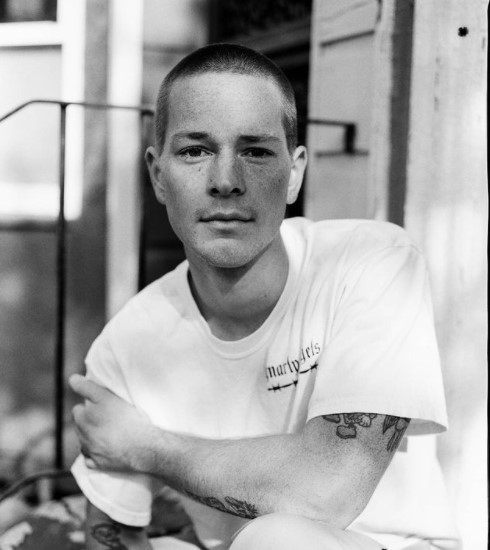 a black and white photo of a man with tattoos