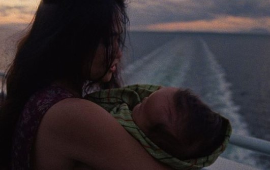 a woman holding a baby on the back of a boat