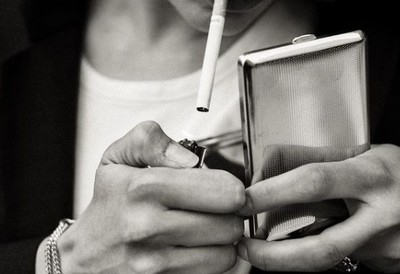 a woman smoking a cigarette and looking at her cell phone