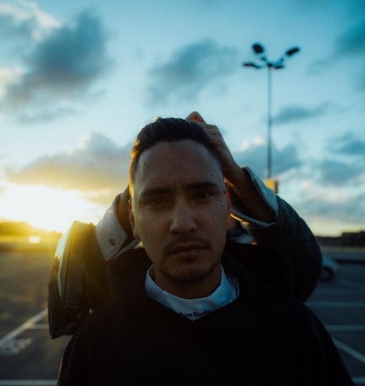 a man standing in a parking lot holding a cell phone to his ear