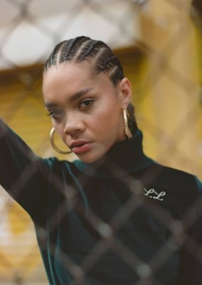 a woman wearing a black turtle neck top and gold hoop earrings