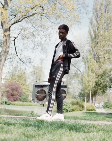 a man standing in the grass near a trash can