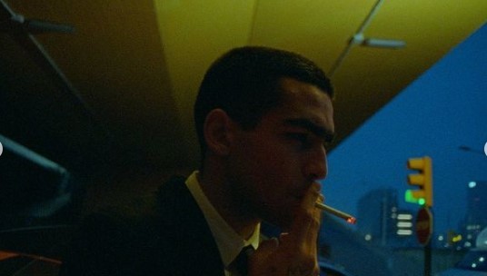 a man in a suit smoking a cigarette