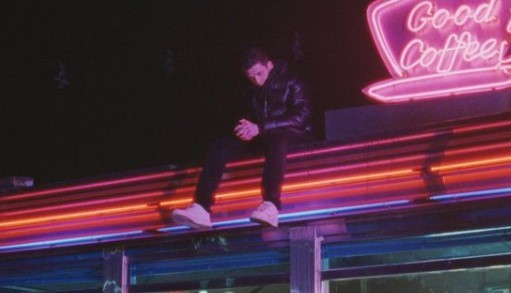 a man standing on top of a building next to a neon sign