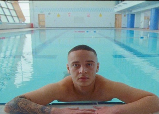 a man with tattoos sitting in a swimming pool