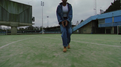 a woman walking across a tennis court holding a glove