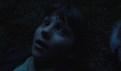 a young boy laying on the ground in the dark