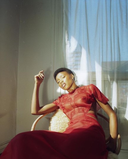 a woman in a red dress sitting in a chair