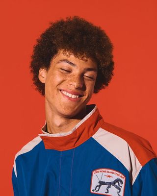 a young man with an afro smiles at the camera