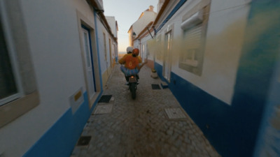 a man riding a motorcycle down a narrow street