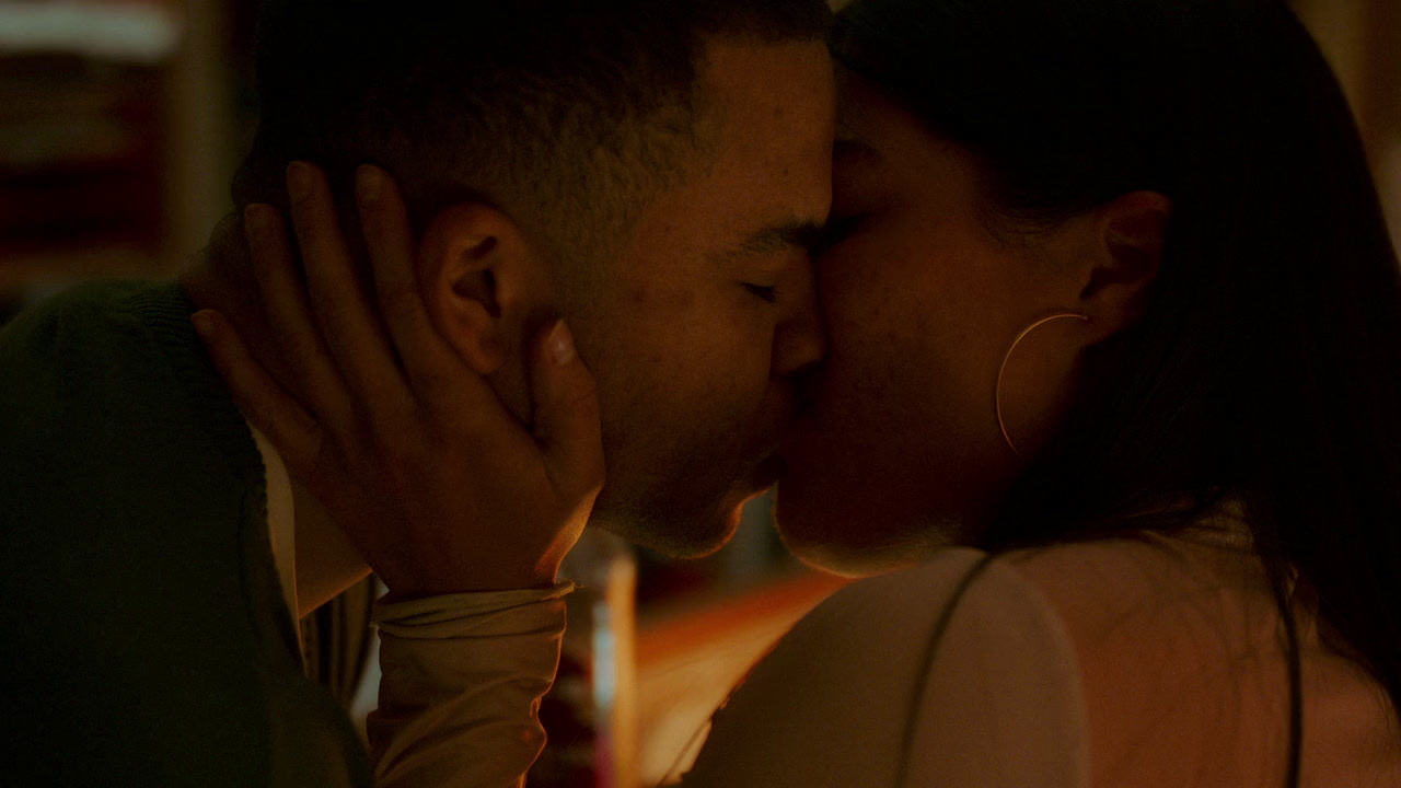 a man and a woman kissing in front of a candle