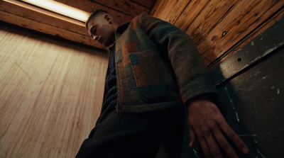 a man standing in a room next to a wooden wall