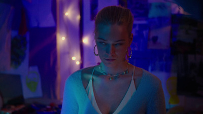 a woman wearing a necklace and earrings in a dark room