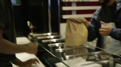 a man holding a brown paper bag in front of a counter