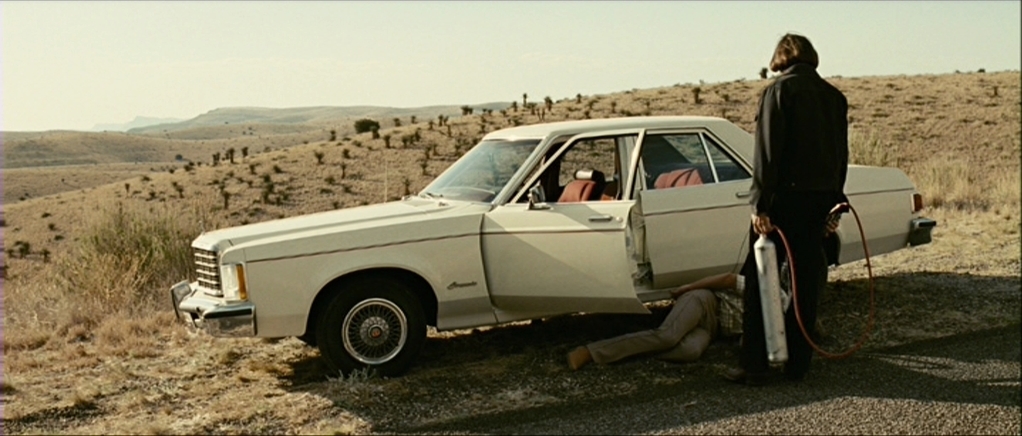 a man standing next to a white car on a dirt road