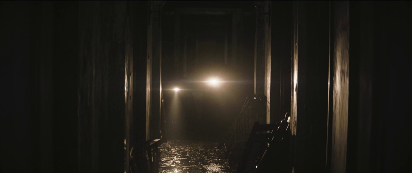 a dark hallway with a light at the end of it