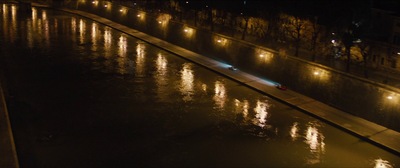 a city street at night with lights reflecting in the water