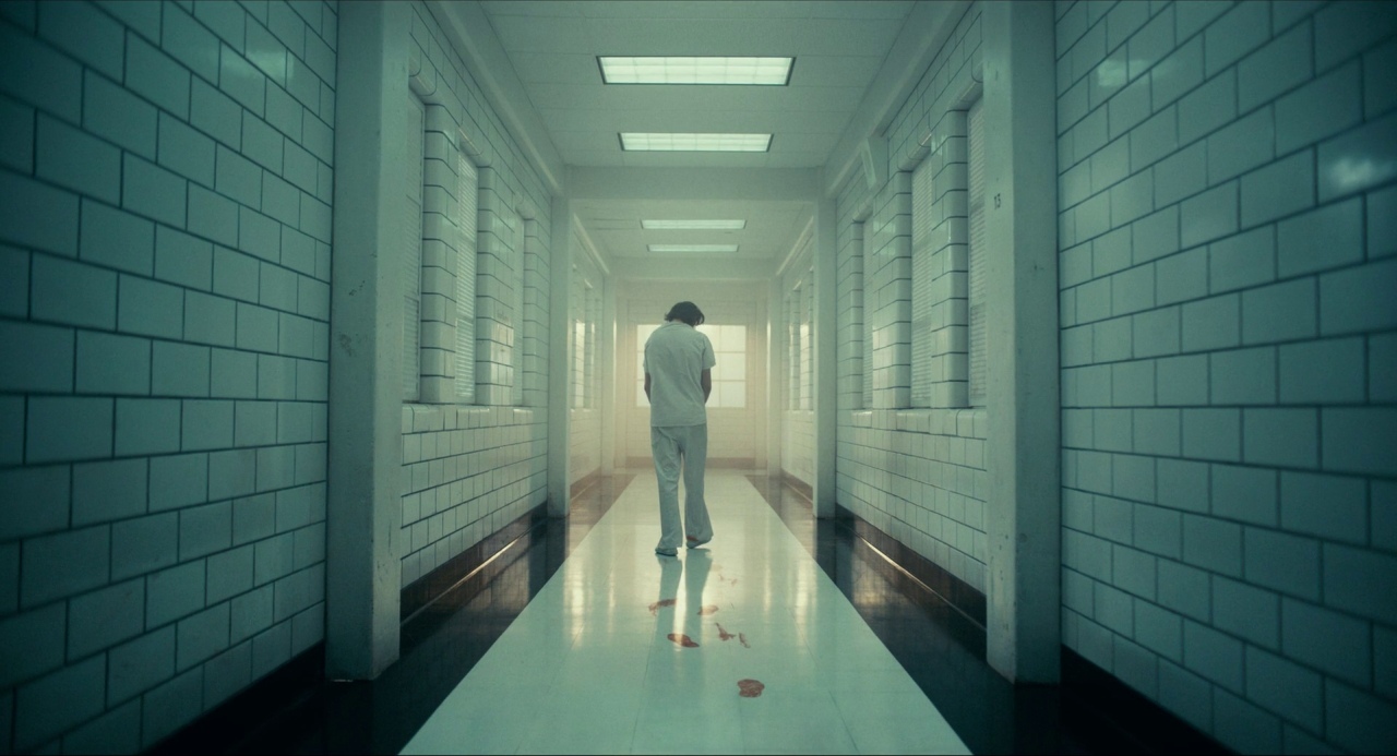 a man walking down a hallway in a white suit