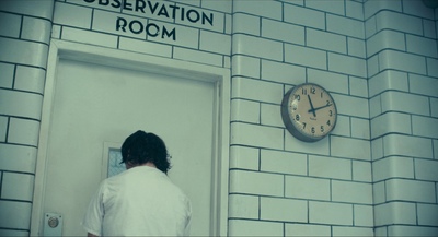 a person standing in front of a door with a clock on the wall