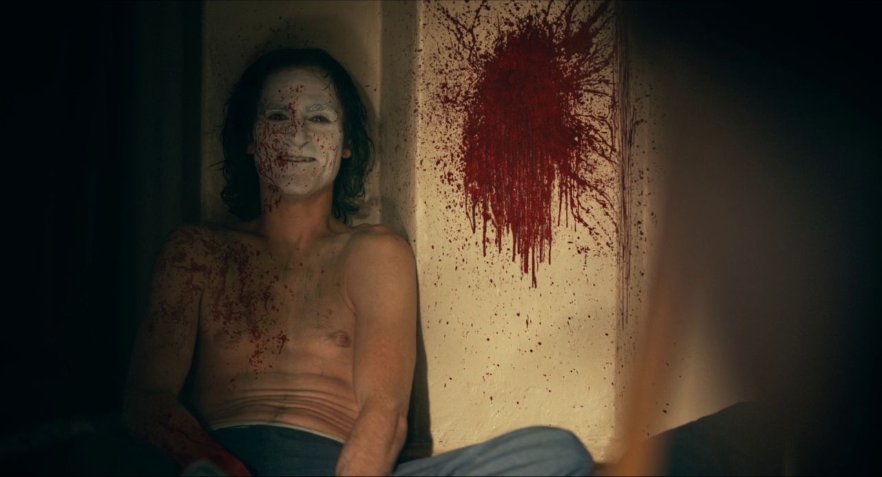 a man with a bloody face sitting in a room