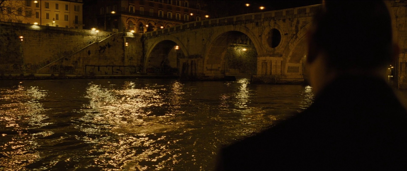 a person standing in front of a bridge at night