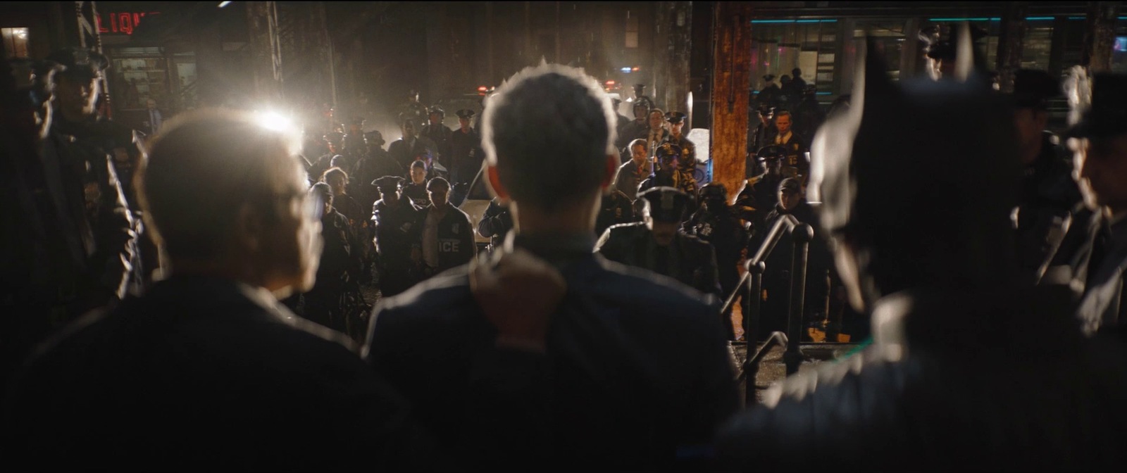 a crowd of people standing around a street at night