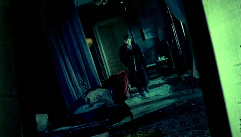 a man standing in a dark room next to a bed