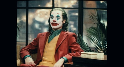 a man dressed as a joker sitting in front of a window