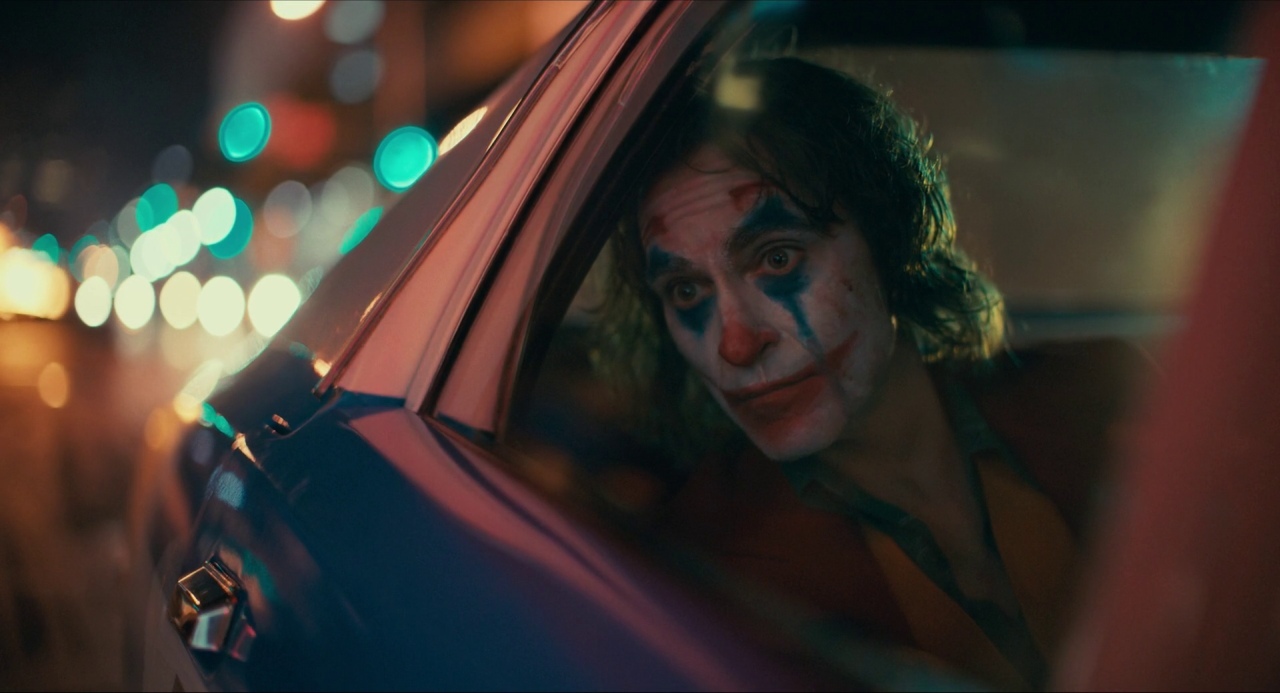 a man in a car with his face painted as the joker