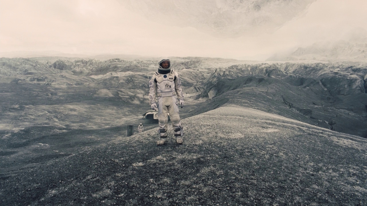 a man in a space suit standing on top of a mountain