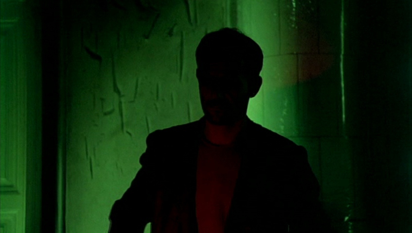 a man standing in a dark room with a green light