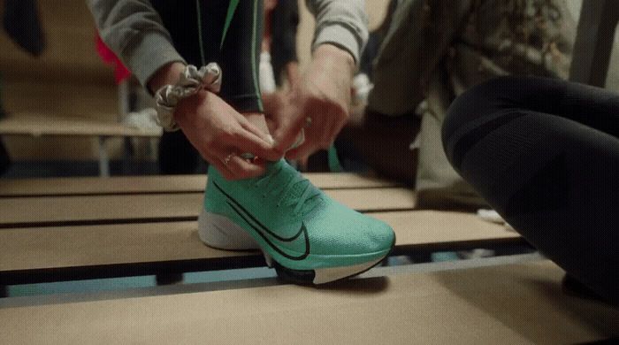 a person tying a shoelace to another person's shoe