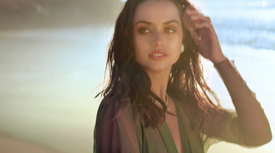 a woman standing on a beach with her hair blowing in the wind