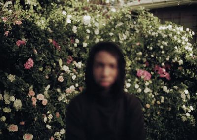 a person standing in front of a bush of flowers