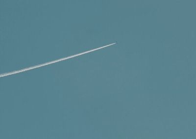 an airplane flying in the sky with a contrail