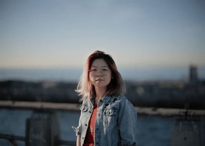 a woman in a jean jacket standing on a balcony