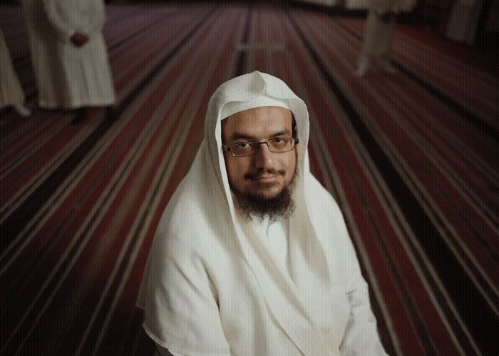 a man with a beard and glasses sitting in a room