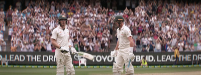 two cricket players walking on a field in front of a crowd