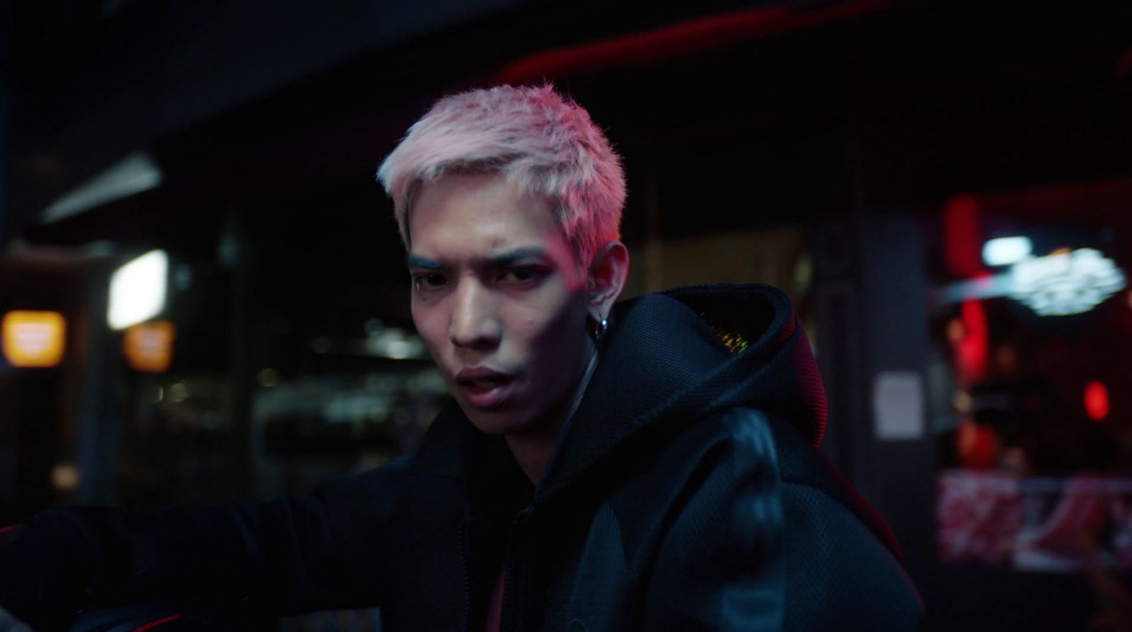 a man with pink hair wearing a black jacket