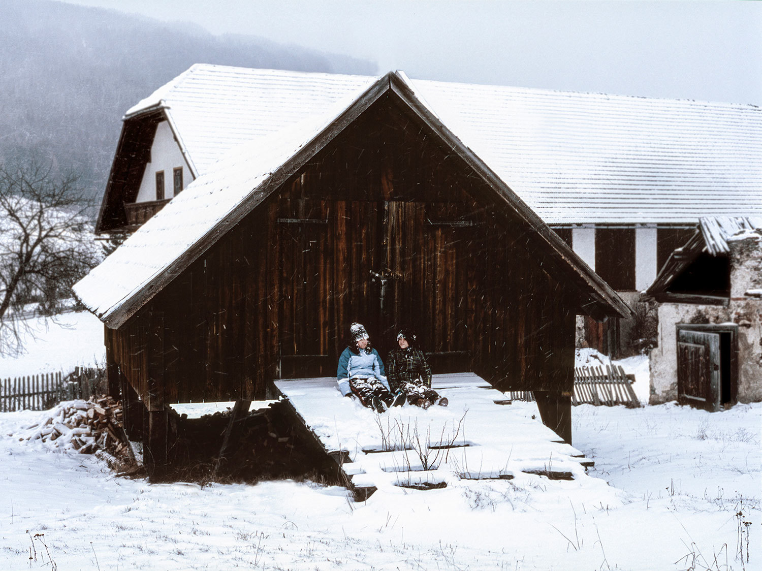 a person sitting on a bench in front of a barn