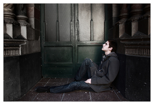 a man sitting on the ground in front of a green door