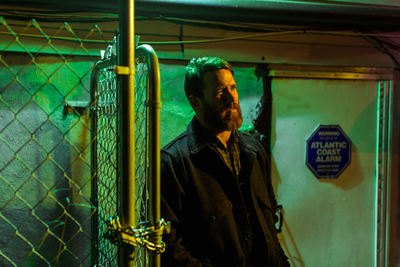 a man standing next to a chain link fence