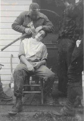 a black and white photo of a man getting his hair cut